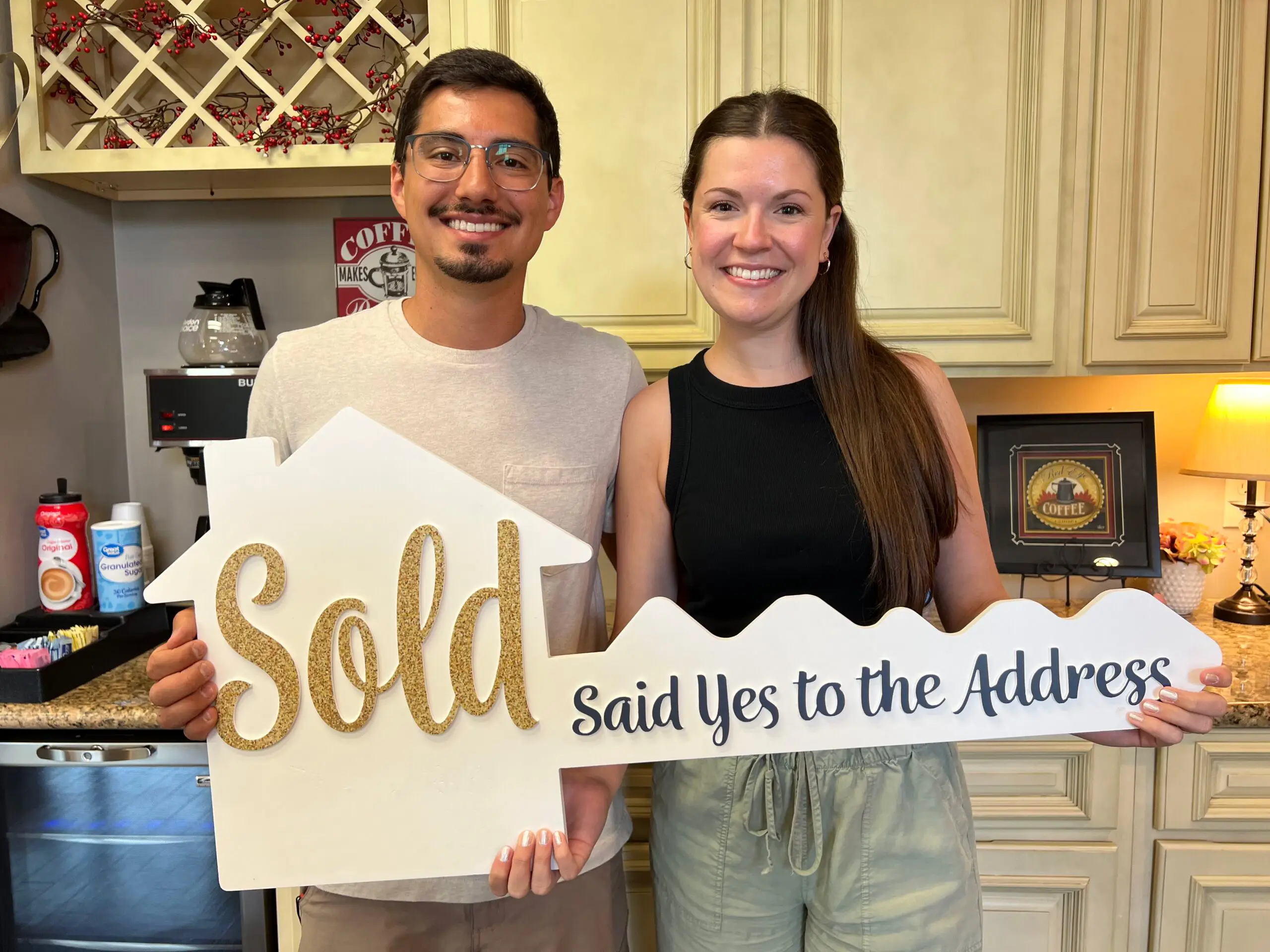 Financing Young couple holding a sign that says sold